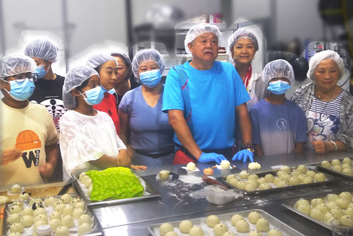 volunteers at professional kitchen making jiaozi buns